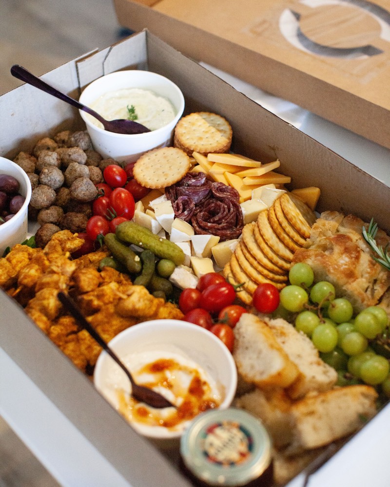 A Daai Platter Boks with bobotie chicken skewers, mini frikkadelle, tzatziki, focaccia, cheese and a jar of Smoked Tomato & Chilli Jamney